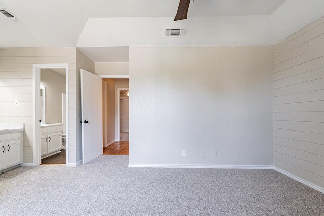 unfurnished bedroom with ceiling fan, light carpet, and ensuite bathroom