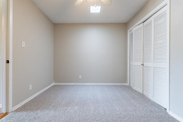 unfurnished bedroom featuring a textured ceiling, a closet, ceiling fan, and carpet