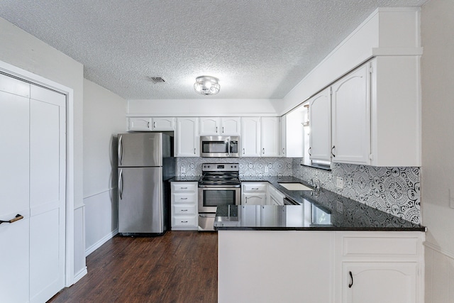 kitchen with decorative backsplash, dark hardwood / wood-style flooring, white cabinetry, kitchen peninsula, and stainless steel appliances