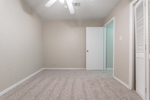 carpeted spare room featuring ceiling fan and a textured ceiling