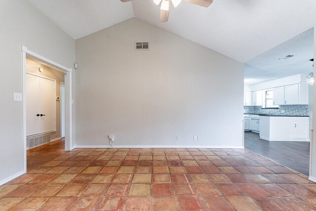 unfurnished living room featuring a textured ceiling, ceiling fan, light tile patterned floors, and vaulted ceiling