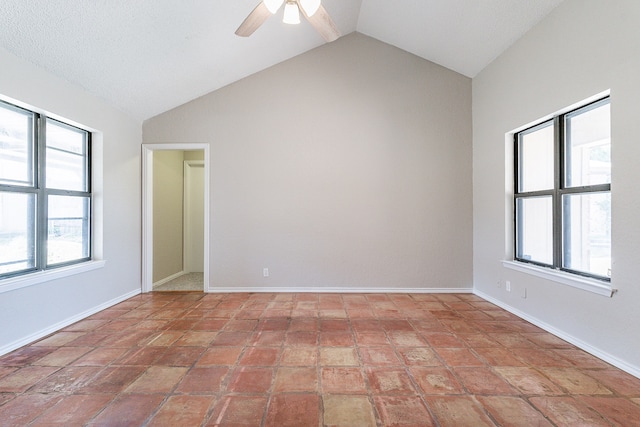 empty room featuring a wealth of natural light, vaulted ceiling, and tile patterned floors