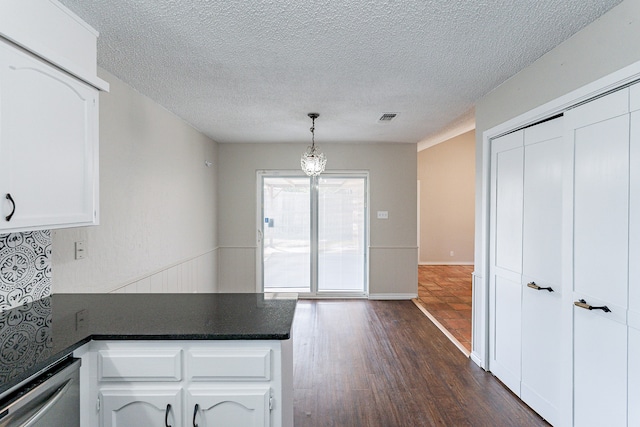 kitchen featuring dark wood-type flooring, decorative light fixtures, a textured ceiling, and white cabinets