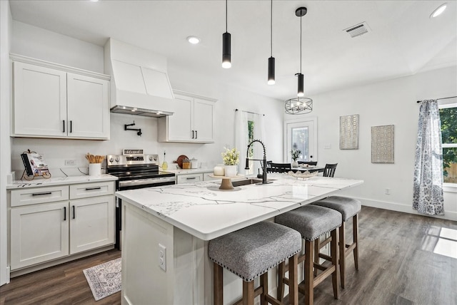 kitchen featuring dark hardwood / wood-style floors, a center island with sink, premium range hood, electric stove, and white cabinets