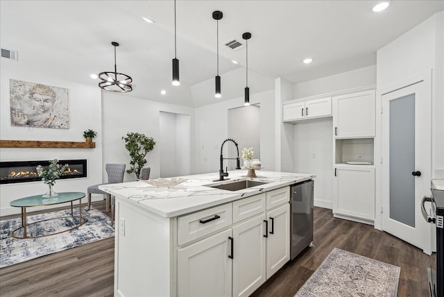 kitchen featuring decorative light fixtures, light stone counters, sink, an island with sink, and dark wood-type flooring