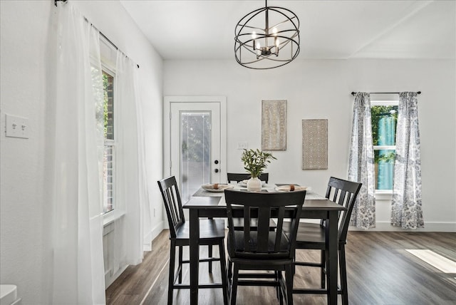 dining area with dark wood-type flooring, a wealth of natural light, and a chandelier