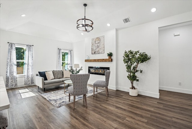 living room with dark hardwood / wood-style floors and an inviting chandelier