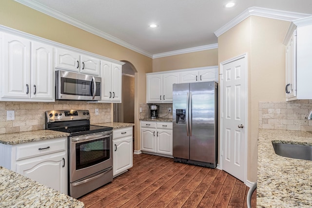 kitchen with ornamental molding, white cabinetry, tasteful backsplash, dark wood-type flooring, and appliances with stainless steel finishes