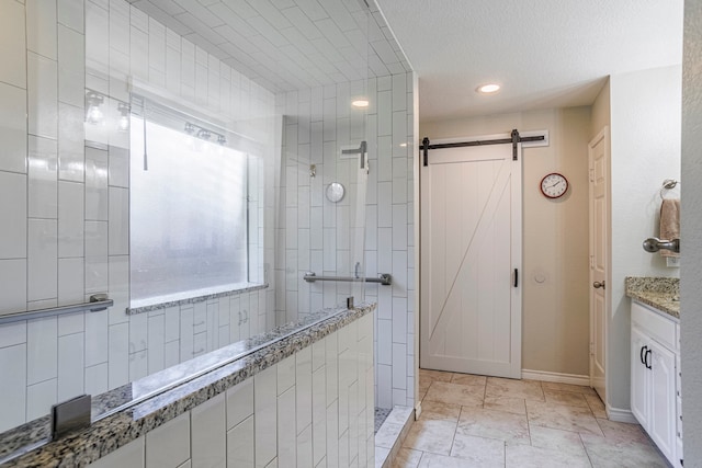 bathroom with tile patterned floors, tile walls, vanity, tiled shower, and a textured ceiling