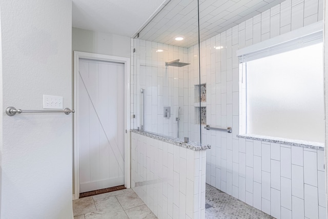 bathroom with tile walls, tile patterned floors, and a tile shower