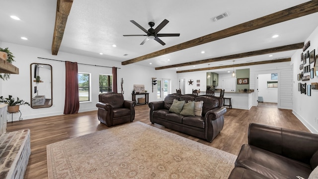 living room with beamed ceiling, wood-type flooring, and ceiling fan