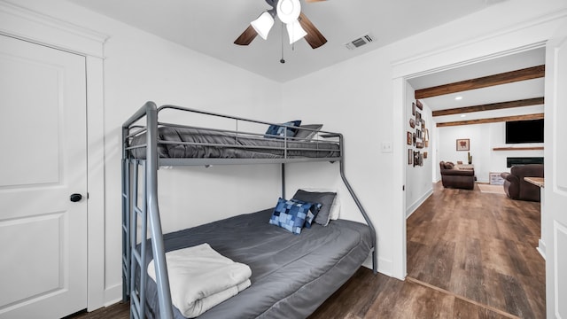 bedroom with dark wood-type flooring, beamed ceiling, and ceiling fan