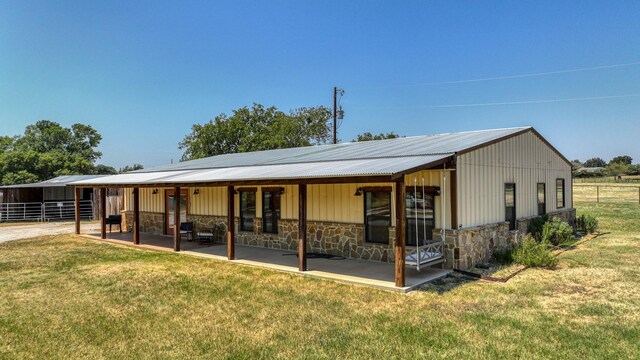 133 Prairie Ln, Weatherford, TX 76087 - back of house with stone siding, an outbuilding, an exterior structure, and metal roof
