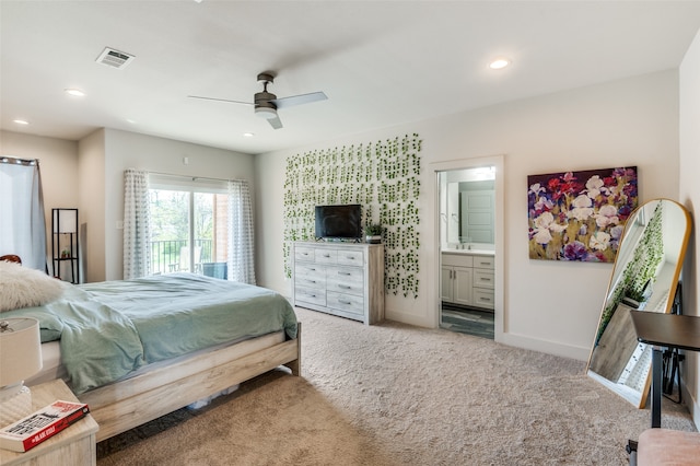 bedroom with ceiling fan, light colored carpet, and ensuite bathroom