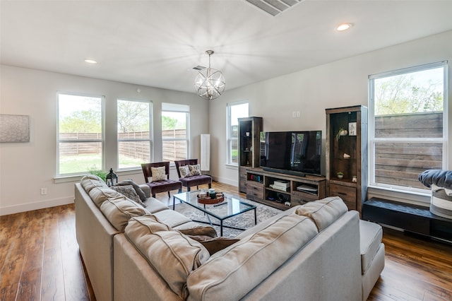 living room with a wealth of natural light, a notable chandelier, and wood-type flooring