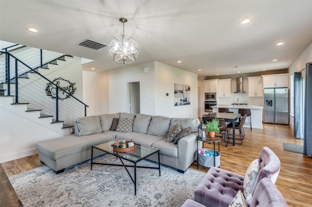 living room featuring a notable chandelier, sink, and light wood-type flooring