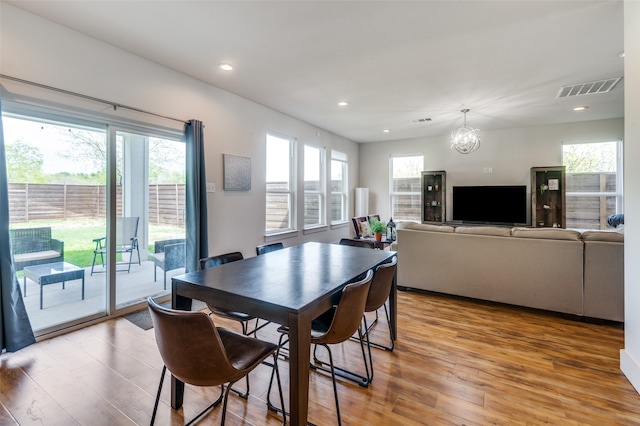 dining space with a healthy amount of sunlight, a chandelier, and light hardwood / wood-style floors