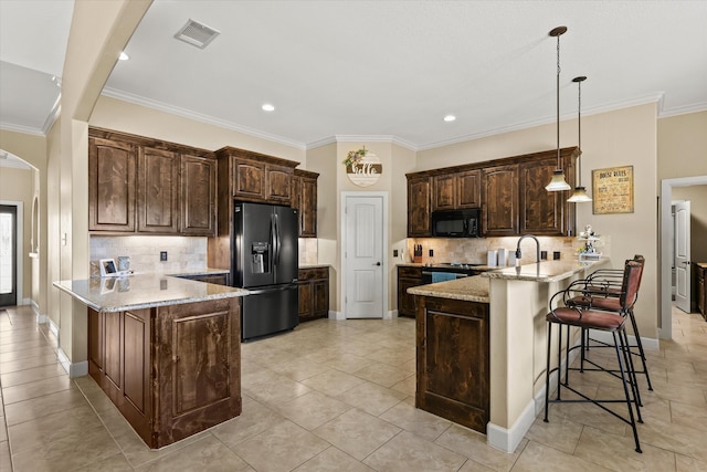 kitchen featuring hanging light fixtures, light stone countertops, black appliances, dark brown cabinets, and kitchen peninsula