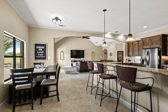 kitchen with light stone countertops, stainless steel refrigerator with ice dispenser, pendant lighting, lofted ceiling, and ceiling fan