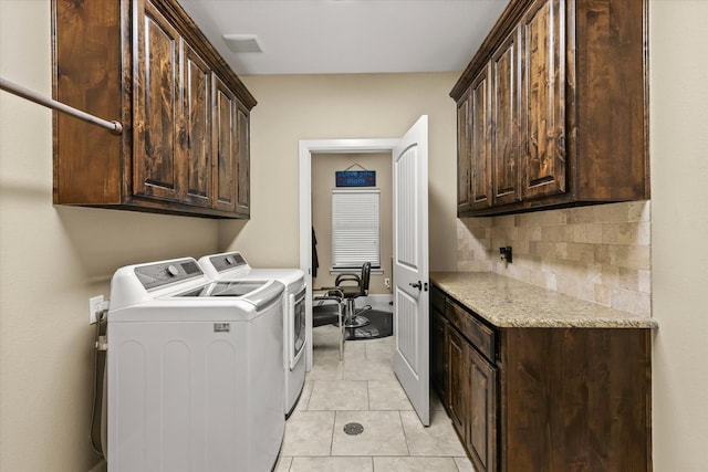 clothes washing area featuring light tile patterned floors, cabinets, and washer and dryer