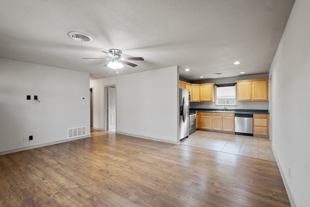 kitchen featuring light brown cabinetry, sink, ceiling fan, appliances with stainless steel finishes, and light hardwood / wood-style floors