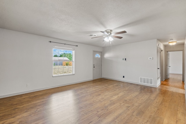 unfurnished room featuring light wood-type flooring, ceiling fan, and a textured ceiling