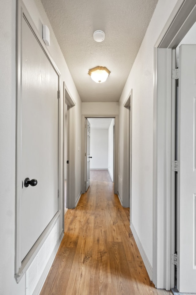 hallway featuring a textured ceiling and light hardwood / wood-style flooring