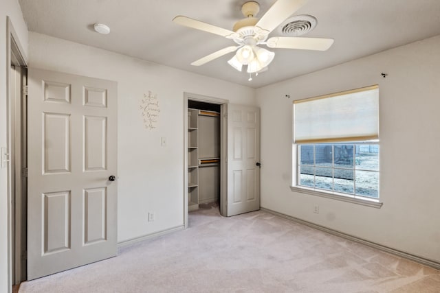 unfurnished bedroom featuring ceiling fan, a spacious closet, and light carpet