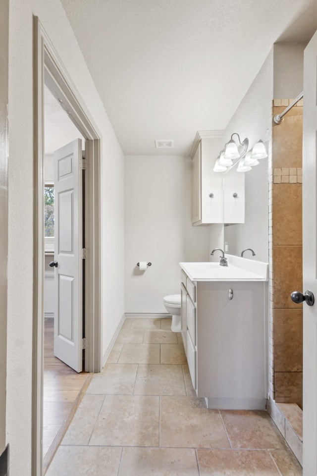 bathroom featuring vanity, toilet, tile patterned floors, and a tile shower