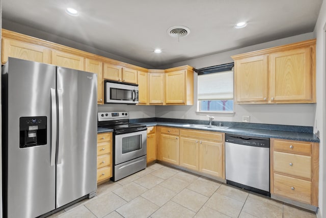 kitchen with light brown cabinetry, sink, stainless steel appliances, and light tile patterned flooring