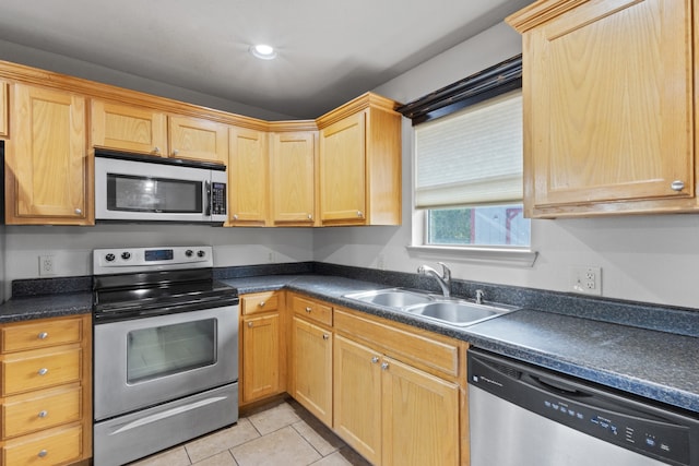 kitchen with stainless steel appliances, sink, and light tile patterned flooring