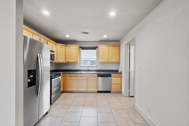 kitchen with light brown cabinetry, stainless steel appliances, sink, and light tile patterned flooring