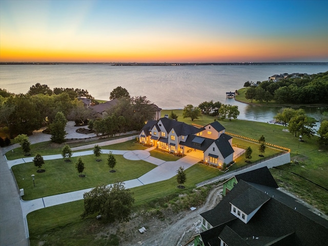 aerial view at dusk featuring a water view