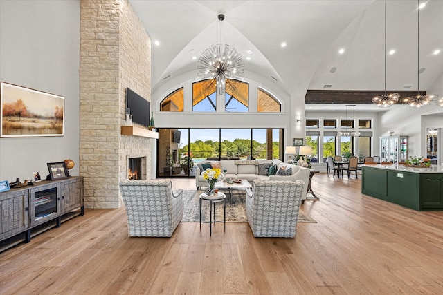 living room with high vaulted ceiling, an inviting chandelier, and light hardwood / wood-style flooring