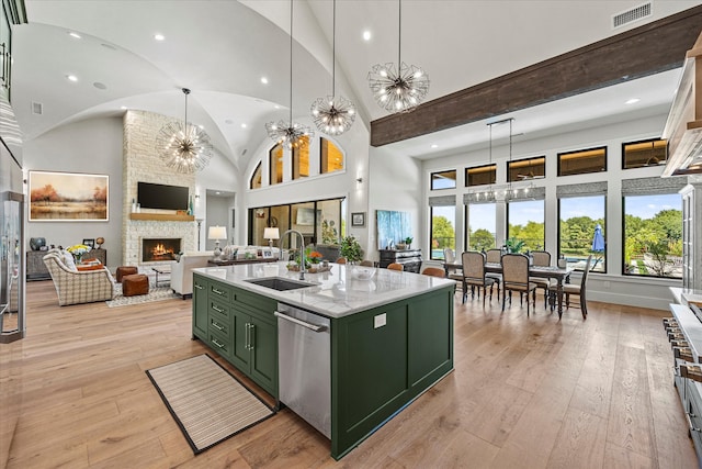 kitchen with green cabinetry, light hardwood / wood-style floors, sink, high vaulted ceiling, and a kitchen island with sink