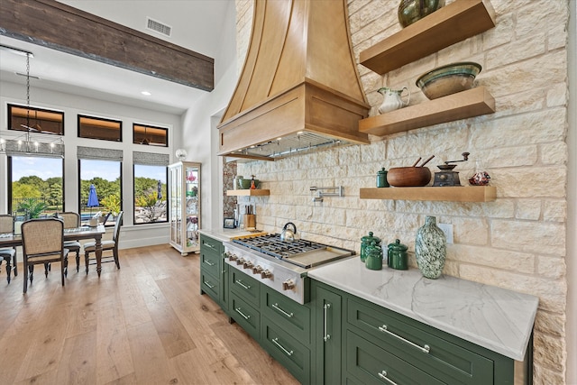 kitchen featuring a high ceiling, green cabinets, light hardwood / wood-style floors, and custom range hood