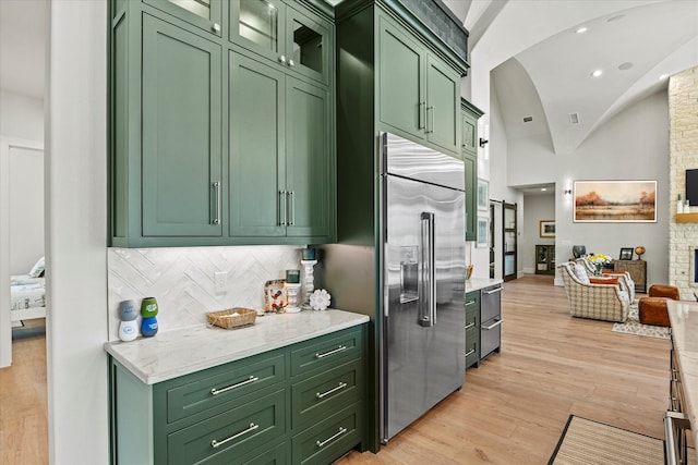 bar featuring lofted ceiling, green cabinetry, appliances with stainless steel finishes, and light hardwood / wood-style flooring