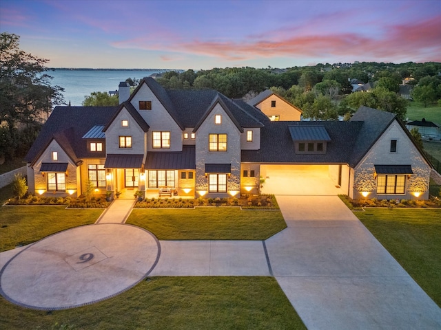 modern farmhouse style home featuring a lawn, a garage, and a water view