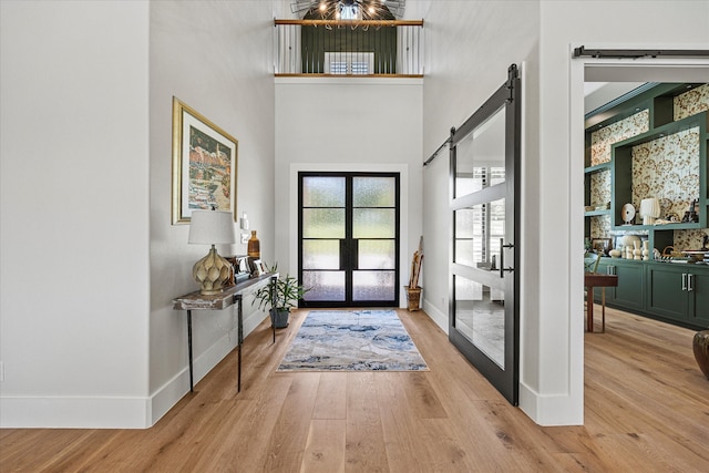 foyer with a towering ceiling, a barn door, and light hardwood / wood-style floors