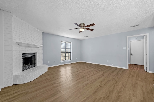 unfurnished living room with a fireplace, a textured ceiling, hardwood / wood-style floors, and ceiling fan