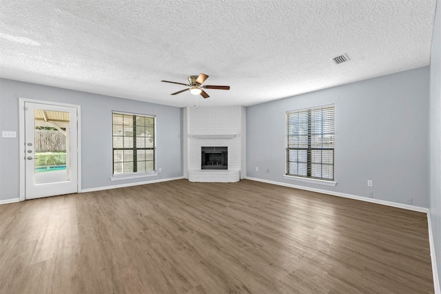 unfurnished living room with wood-type flooring, a fireplace, a textured ceiling, and ceiling fan