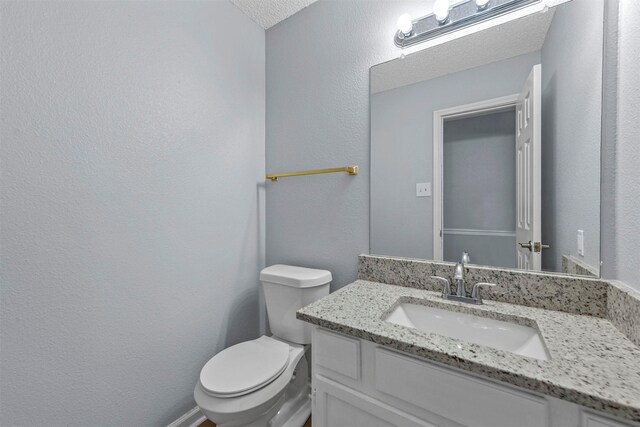 bathroom featuring a textured ceiling, vanity, and toilet