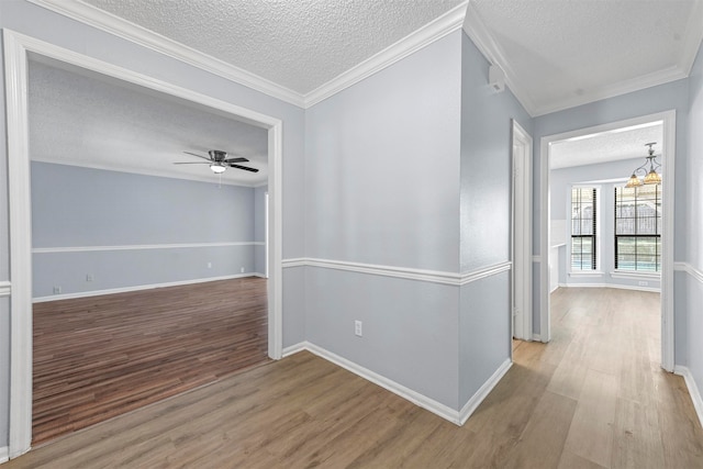 hall with a textured ceiling, ornamental molding, an inviting chandelier, and light hardwood / wood-style floors