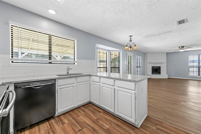 kitchen with a wealth of natural light, stainless steel appliances, wood-type flooring, and a brick fireplace