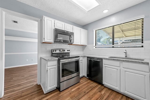 kitchen featuring black appliances, tasteful backsplash, hardwood / wood-style flooring, and light stone countertops