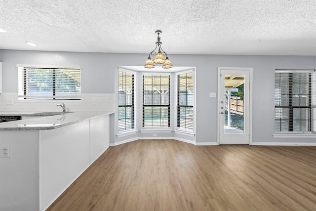 interior space with a textured ceiling, an inviting chandelier, sink, and light wood-type flooring