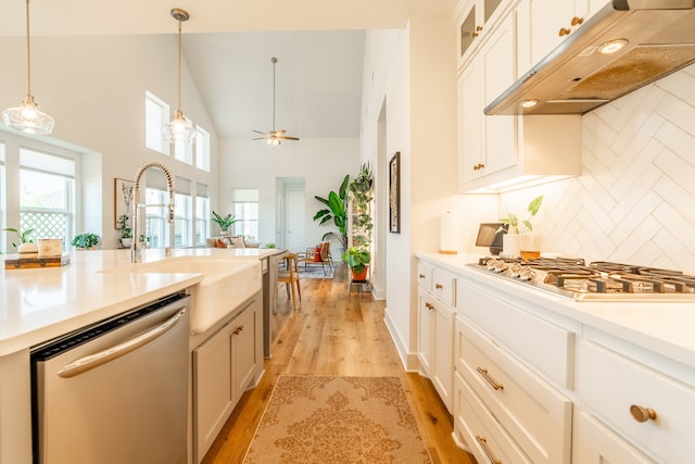 kitchen with pendant lighting, high vaulted ceiling, ceiling fan, light hardwood / wood-style floors, and stainless steel appliances