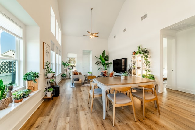 dining space featuring ceiling fan, high vaulted ceiling, and light wood-type flooring