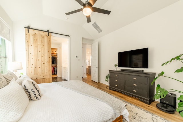 bedroom with a spacious closet, ceiling fan, light hardwood / wood-style floors, and vaulted ceiling