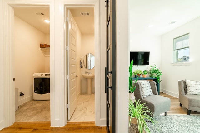 hallway with washer / clothes dryer, light hardwood / wood-style flooring, and sink